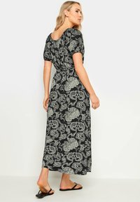 Maxikleid in Schwarz mit weißem Paisleymuster, kurzen Puffärmeln und taillierter Taille. Hergestellt aus leichtem Stoff mit glatter Textur.
