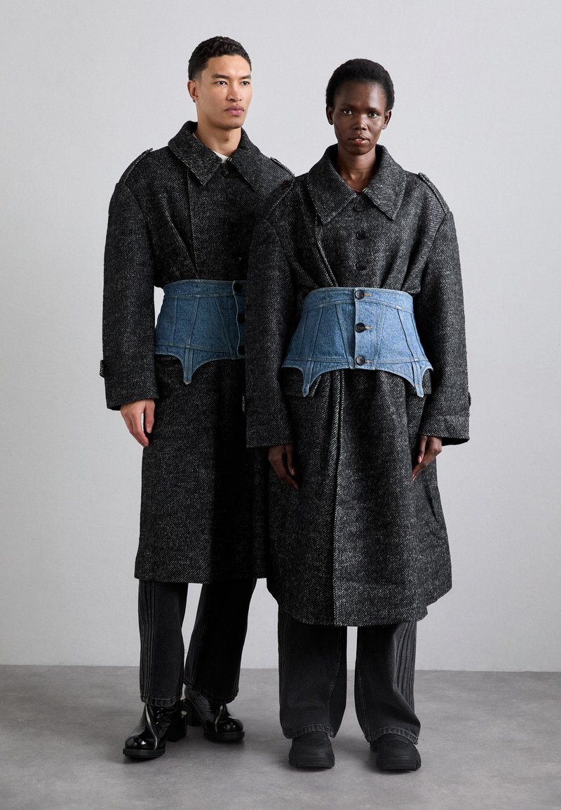 Abrigos largos de lana negra para hombres y mujeres con grandes cuellos, que presentan cinturones estilo corsé de denim azul. Textura suave, detalles de botones visibles.