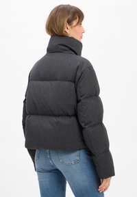 Dunkelgraue Daunenjacke mit hohem Kragen, ausgestattet mit einem gesteppten Design und dicker Polsterung. Das Material wirkt glatt und langlebig.