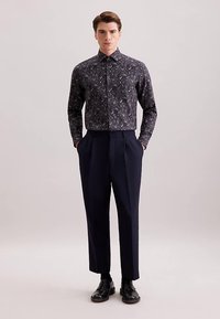 Camicia a maniche lunghe con motivo scuro e abbottonatura, abbinata a pantaloni navy a vita alta e su misura e scarpe in pelle nere.