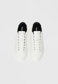 Witte sneakers met een glad leren bovenwerk, zwarte accenten op de kraag en een platte rubberen zool. Beschikt over een vetersluiting en geperforeerde details.