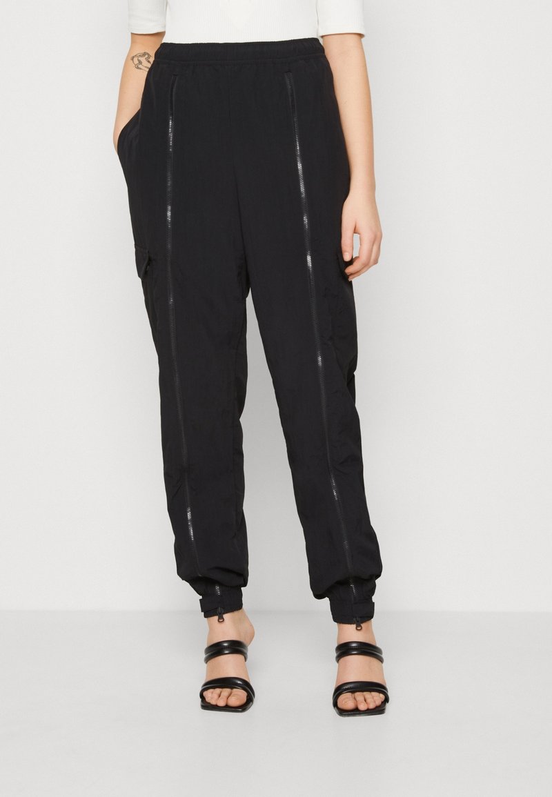 Svarta, lätta joggerbyxor med elastisk midja, blixtlåsfickor fram och elastiska fållar för en smal passform. Sidofickor ingår.