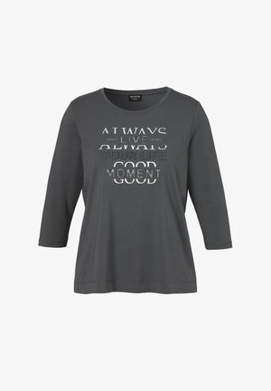 Chemise à manches longues gris foncé avec un texte argenté et blanc indiquant « Always live your life good moment » sur le devant.