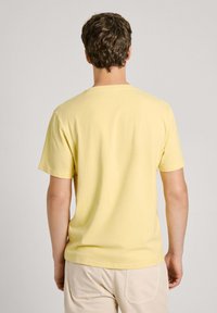 Kortærmet t-shirt med rund hals i lys gul bomuld, der har en glat overflade og en afslappet pasform. Simpelt design uden synlige mønstre.