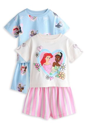 Enfant portant une chemise bleu clair avec des princesses dessinées dans des cadres colorés et des nœuds décoratifs imprimés sur le tissu.