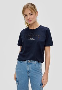 T-shirt en coton bleu marine à manches courtes avec un imprimé texturé "HAPPY" et un texte supplémentaire en dessous. Associé à un pantalon cargo bleu clair.