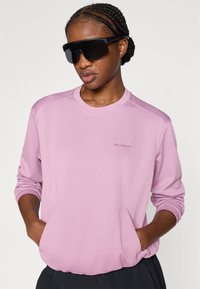 Ανοιχτό μωβ μακρυμάνικη μπλούζα από δίχτυ με στρογγυλή λαιμόκοψη και πλαϊνές τσέπες. Διαθέτει υφασμένο σχέδιο και μικρό λογότυπο στο στήθος.