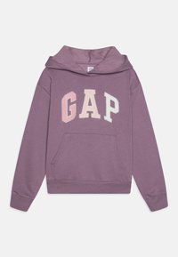 Sudadera de algodón morada con un bolsillo frontal, que presenta un gran logotipo "GAP" en rosa y blanco. Textura suave, diseño tipo canguro.