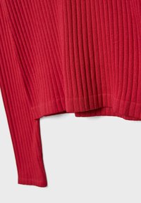 Pull rouge à côtes avec un tricot texturé, manches longues et une coupe décontractée avec un ourlet légèrement court.