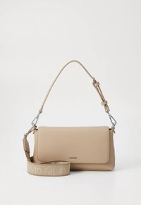Beige læderhåndtaske med klaplukning, justerbar rem og sølvfarvet beslag med en logo på en struktureret rem.