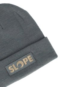 Grijze gebreide muts met een opgerolde rand. Voorzien van een rechthoekig label met het woord "SLOPE" in gouden letters op een grijze achtergrond.