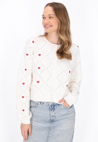 Bílý cardigan s červenými srdíčky, texturovaný otevřený úplet v diamantovém vzoru, s knoflíkovým zapínáním a pružnými manžetami a spodním lemem.