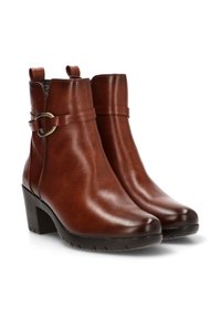 Botines de cuero marrón con punta redonda, tacón alto y ancho, y una correa decorativa con hebilla alrededor del tobillo. Textura suave, diseño minimalista.