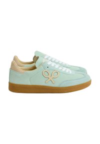 Zapatillas de ante verde claro con un talón y cordones beige, que cuentan con un destacado detalle de logo en marrón y una suela de goma texturizada.