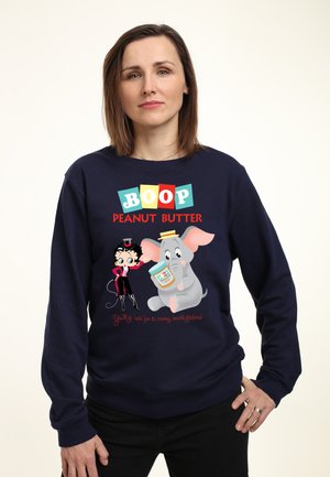 Marineblå sweatshirt med farverige tegneserieillustrationer af en karakter og en elefant, der holder et glas peanutbutter med tekst.