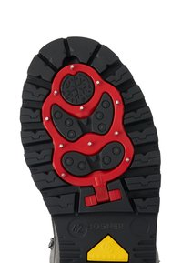 Sole lyžařské boty s černým gumovým vzorem, červené protiskluzové hroty s kovovými špičkami, rytí velikosti 42 a žlutá systémová značka.