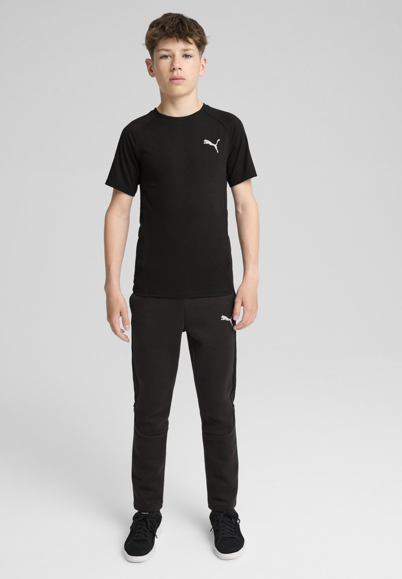 Melna īsām piedurknēm T-kreklā ar Puma logotipu, apvienota ar melniem pieguļošiem sporta biksēm ar sānu kabatām un mazu logotipu uz gurniem.