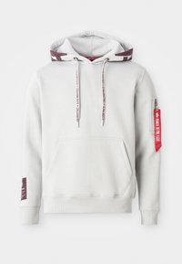 Sweat à capuche gris clair avec une poche avant, une capuche avec cordon de serrage et des poignets côtelés. Comprend une poche zippée rouge et des accents de texte décoratifs.