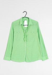 Zelená košile s dlouhým rukávem a zapínáním na knoflíky, s volánkovým detailem u výstřihu, dvěma náprsními kapsami a hladkým, lehkým materiálem.
