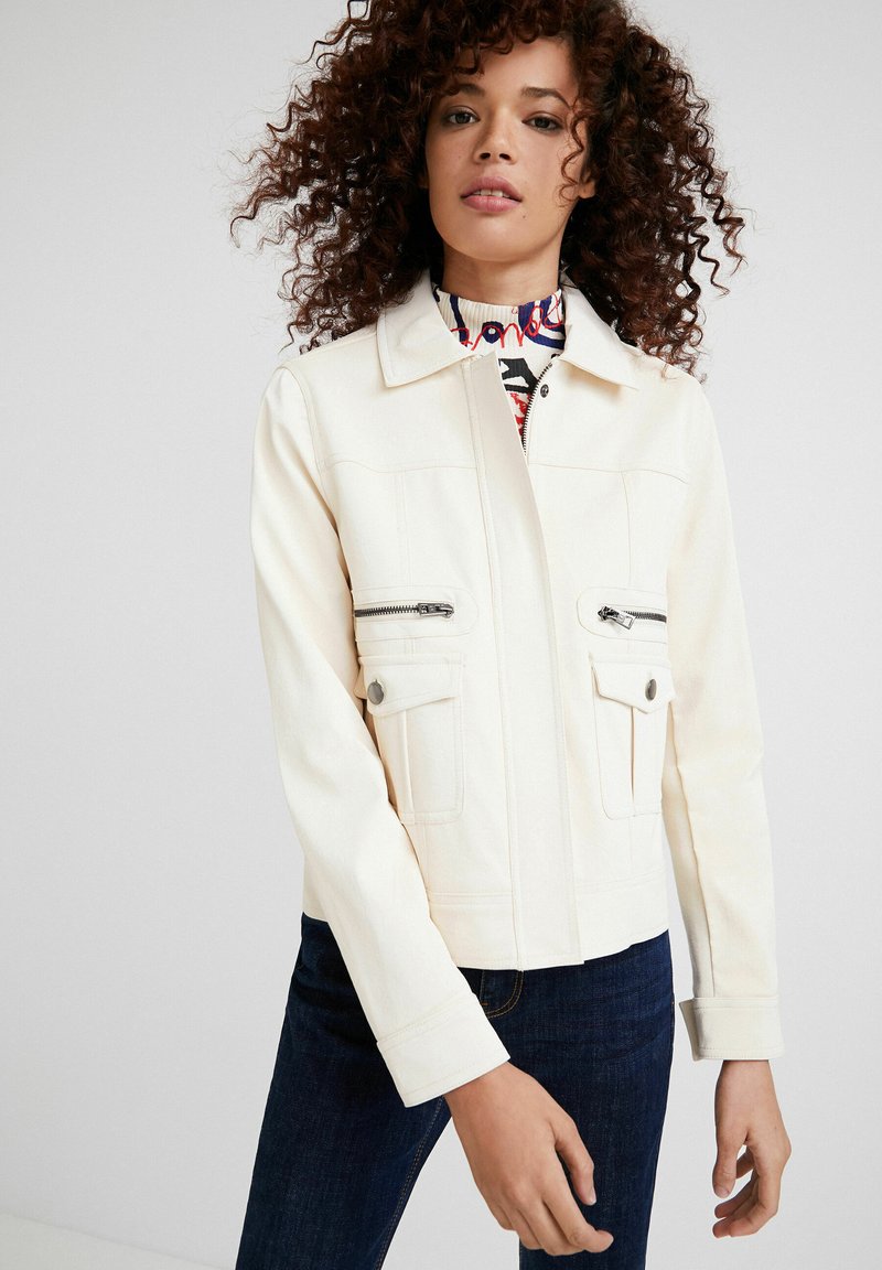 Witte spijkerjack met een kraag, voorzien van twee borstzakken met rits en twee lagere klepzakken. Slim fit met een cropped lengte en omgeslagen mouwen.