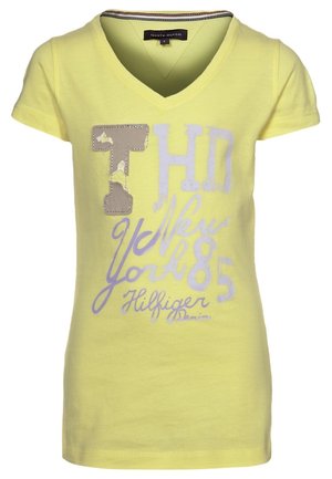 T-shirt gialla a maniche corte con scollo a V con scritte "THD", "New York", "85" e "Hilfiger Denim" e toppe sulla parte anteriore.