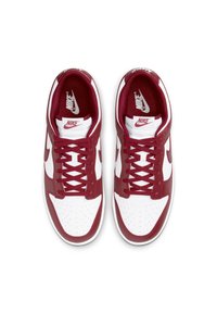 Nike sneakers in red and white, featuring a perforated toe box, lace-up design, padded collar, and branded tongue. Smooth leather finish.