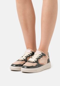 Tenisky s kombinací semiše a lesklé kůže v béžové a tmavě zelené barvě. Obsahují texturované akcenty, krémové šněrování a silnou podešev.