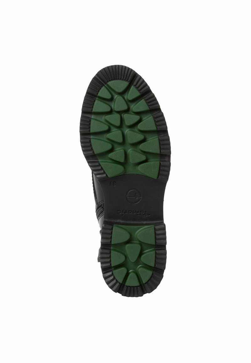 Suola di scarpa nera con una trama di gomma verde, caratterizzata da elementi di trazione triangolari e un logo circolare sul tallone.