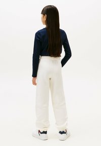 Marineblå langærmet top med ribbet tekstur, parret med hvide sweatpants med elastisk talje, afsluttet med hvide sneakers.