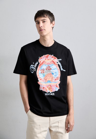 Camiseta de algodón negra con un gráfico colorido inspirado en el Mediterráneo que incluye elementos marinos y el texto "VERSACE" en la parte inferior.