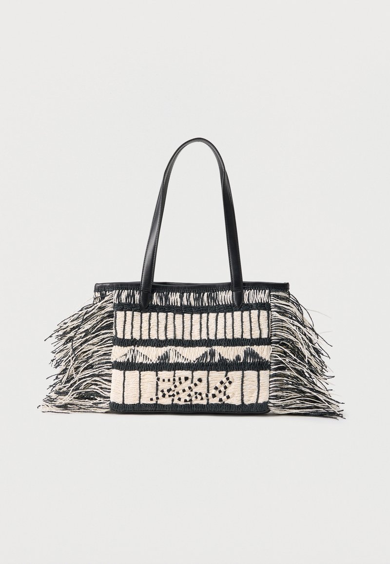 Håndvevd svart og hvit rektangulær handlenett med geometriske mønstre og lange frynser på sidene, med svarte skulderremmer i lær.