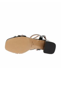 Sanda negra de tacón alto con un upper de cuero suave, un tacón cuadrado y una suela de goma beige con marca en relieve.