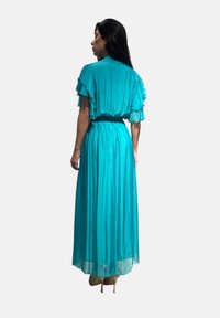 Abito maxi teal con maniche corte a volant, vita cintrata e gonna fluida. Tessuto leggero con una texture liscia.