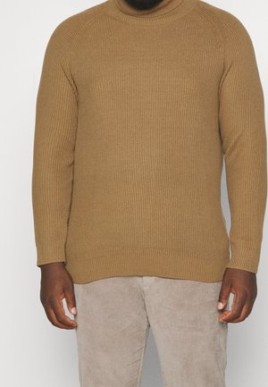 Braun gestreifter Rollkragenpullover aus strukturiertem Stoff mit langen Ärmeln, kombiniert mit hellbeigen Cordhosen.