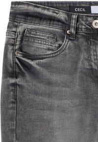 Zbliżenie czarnych jeansów z denimu z przednią kieszenią, małą kieszonką na monety, szlufką na pasek, metalowym guzikiem i widoczną etykietą marki Cecil.