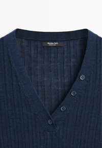 Cardigan in maglia coste blu navy con scollo a V e quattro bottoni abbinati sul davanti, etichetta Massimo Dutti all'interno del colletto.
