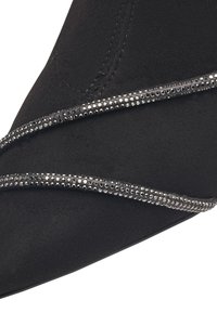 Pointu en daim noir avec deux sangles noires en diagonale ornées de petits strass en argent.