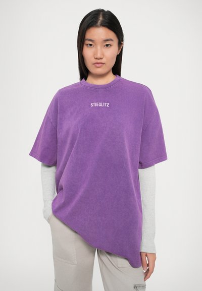 Lilla oversized t-skjorte med rund hals, med teksten "STIEGLITZ" i hvitt. Myk tekstur, kortermet og avslappet passform.