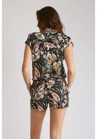 Ensemble floral noir comprenant un haut à manches courtes et un short, avec des imprimés tropicaux vibrants en vert, rose et blanc, doté d'une coupe décontractée et d'une taille élastique.