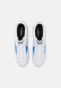Pantofi sport albi cu accente albastre, av�ând un superior din piele netedă, șireturi plate, limbă căptușită și branț negru cu text auriu.