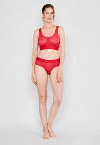 Red lingerie set consisting of a sheer, wave-patterned bralette and matching panties with wide bands. Stretchy, fitted design.