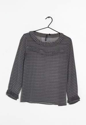 Long-sleeve top in black and white geometric pattern, with a round neckline and rolled cuffs, made of lightweight fabric.