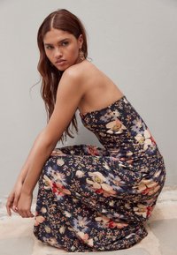 Sukienka bez ramiączek w granatowym kolorze z kwiatowym nadrukiem, ozdobiona dużymi pastelowymi kwiatami i dopasowanym gorsetem. Gładka faktura z lejącym się dołem.