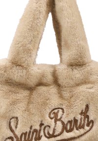 Bolso tote de piel de imitación beige con textura suave y asas blandas; presenta el texto bordado "Saint Barth" en marrón.