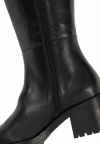 Zwarte leren kniehoge laars met een rits aan de zijkant, gestructureerd oppervlak, chunky hak en profielzool voor betere grip.