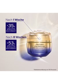 Shiseido Vital Perfection Creme in einem zweifarbigen Glas — Gold- und Blauverlauf, glatte Textur, runde Form, mit klarer Produktkennzeichnung.