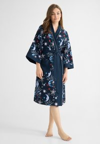 Mörkblå kappa med himmelska mönster av stjärnor och månar, med lösa ärmar, knytmidja och framficka. Mjuk tygkvalitet.