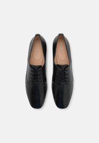 Black leather shoes with a smooth finish, rounded toe, and lace-up design. Features two small metallic accents on the sides.