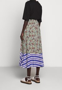 Sukně s květinovým paisley vzorem v zelené barvě, přecházející do modrého a bílého pruhu na lemu. Má nařasený pas a volný siluetu.