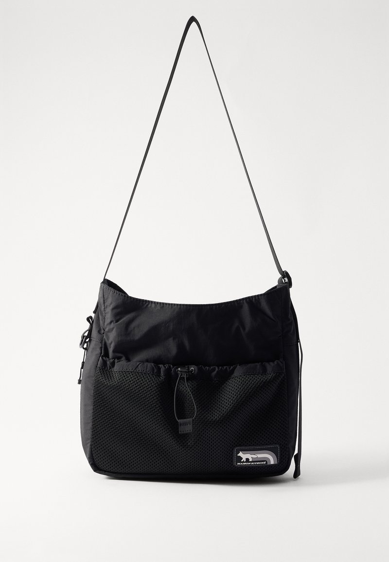 Juodas peties krepšys, pagamintas iš nailono, su tekstūruotu megzto tinklo priekinio kišenės, šnervėmis užsidarančiu viršumi ir reguliuojamu dirželiu. Yra logotipo pleistras.